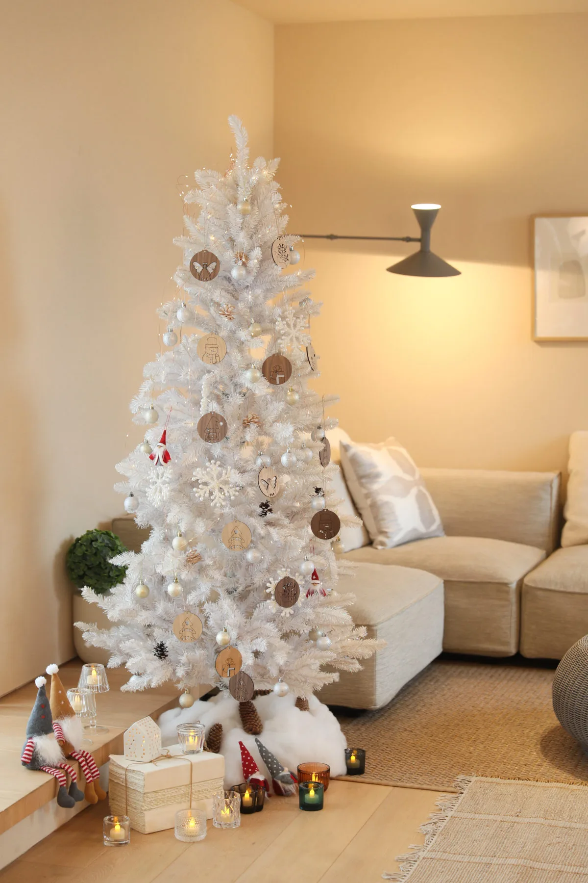 リビングルームの白いクリスマスツリーに天然木オーナメントと銀のボールを混ぜて飾ったナチュラルなコーディネート