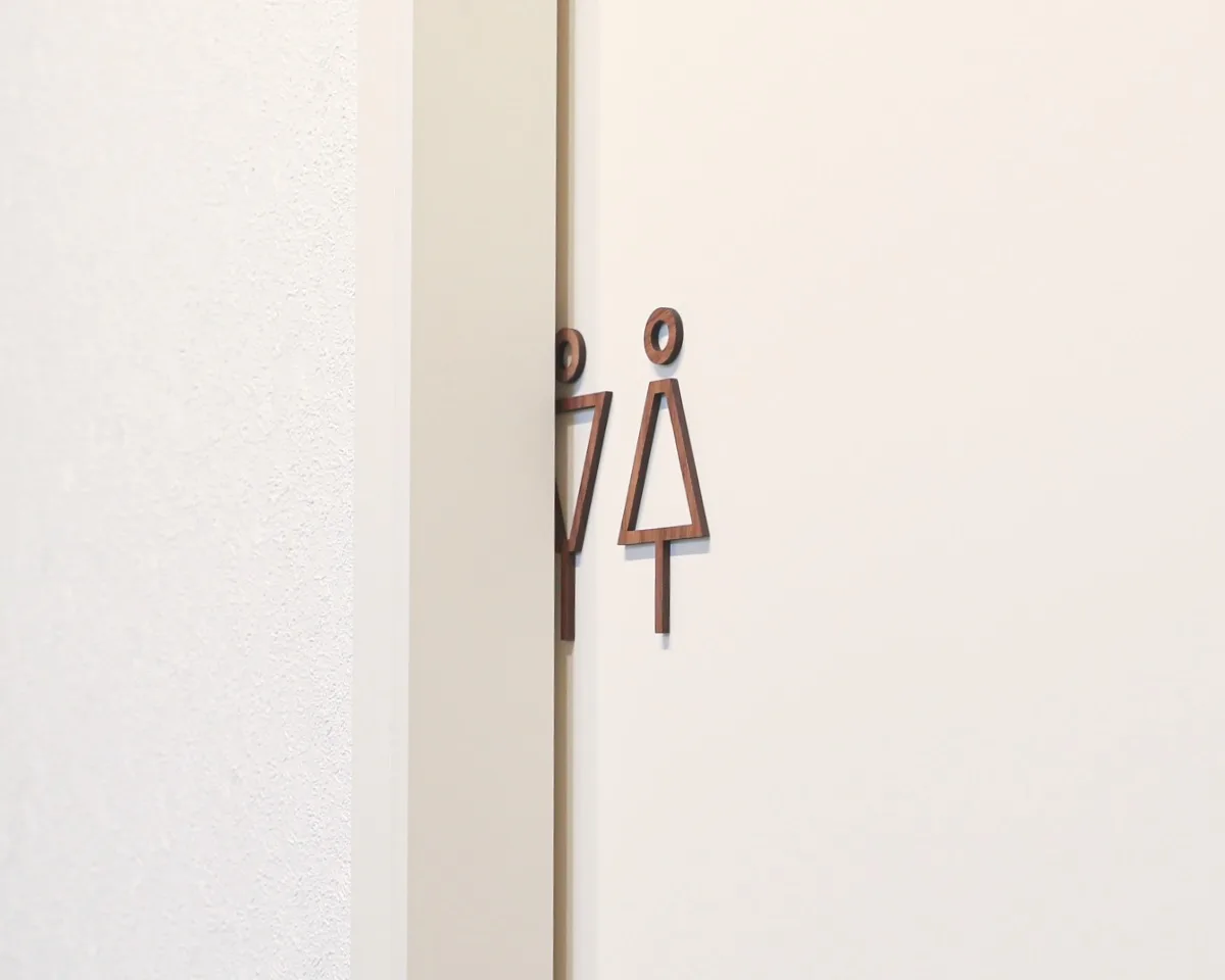 ウォールナット製男女ピクトグラムのトイレサインプレートを引き戸に貼り付けた薄型デザイン例