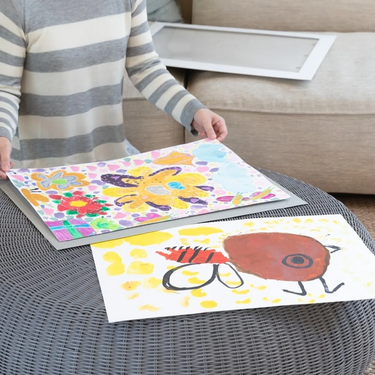 4つ切り画用紙の子どもの絵2枚を台紙に差し込む作業シーン