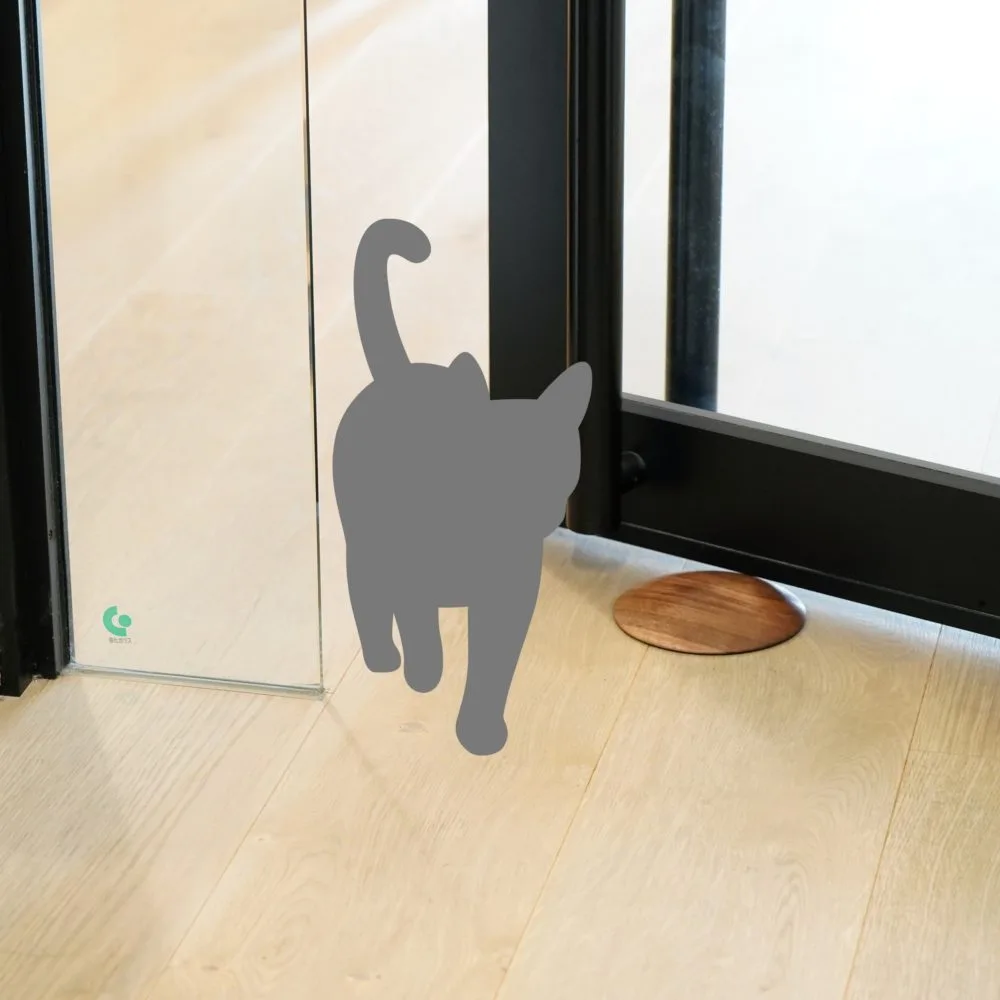 猫のシルエットと開いたドアの傍らに置かれた木製ドアストッパー、ペット安全対策のイメージ