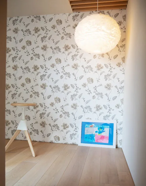 花柄壁紙の部屋の床に立てかけた子供の絵入りペーパーフレーム