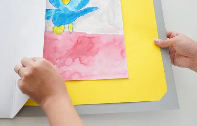 子供の絵を乗せた台紙をペーパーフレームに差し込む手順
