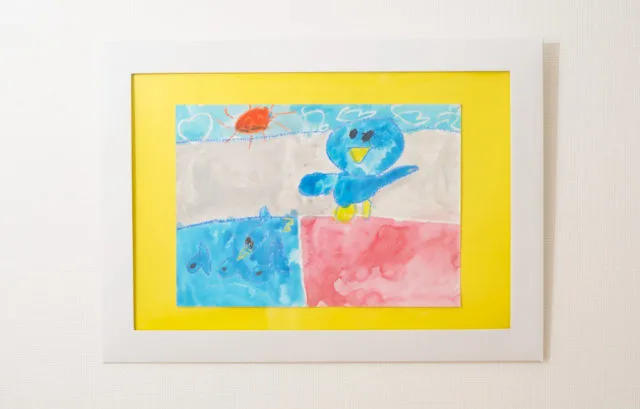 ペーパーフレームに青い鳥の子供の絵を黄色マットで飾った完成例