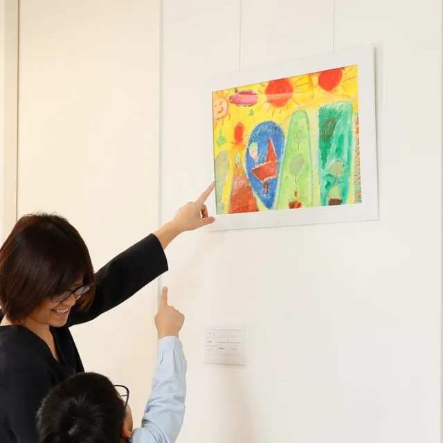 ペーパーフレームに入れた子どもの絵を母子で眺めるシーン