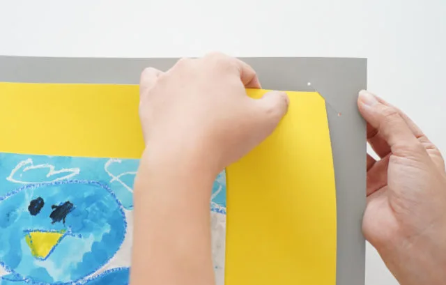 ペーパーフレームの台紙にペンギンの絵を差し込む手元