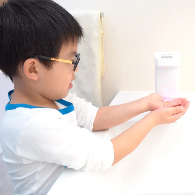 メガネをかけた子どもがオートディスペンサーで手洗いをしている様子