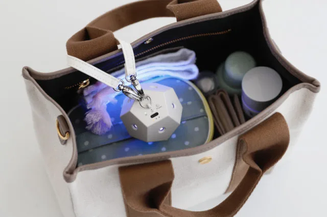 トートバッグの中でストラップに付けられ青いUV光を放つ小型除菌ライトLUCE