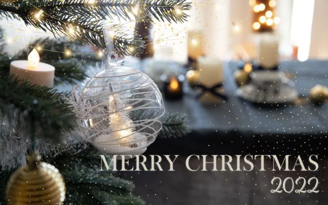 クリスマスツリーのガラスオーナメントとLEDキャンドルが灯るテーブル、「MERRY CHRISTMAS 2022」の文字