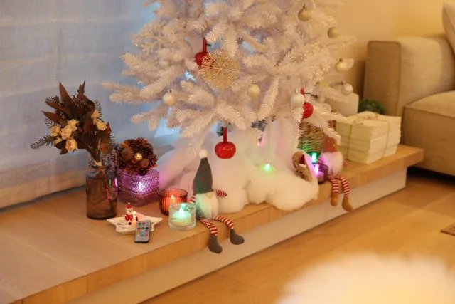 白いクリスマスツリーの足元にLEDキャンドルとトントゥ人形を飾ったインテリアスタイリング